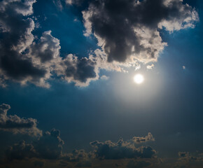 Sun and black clouds in the dark blue sky