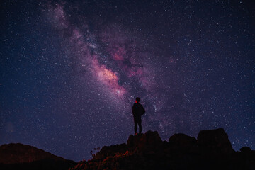 Naklejka na ściany i meble Silhouette of boy / man standing on the hill. Stargazing at Haleakala National Park, Maui, Hawaii. Starry night sky, Milky Way galaxy astrophotography.
