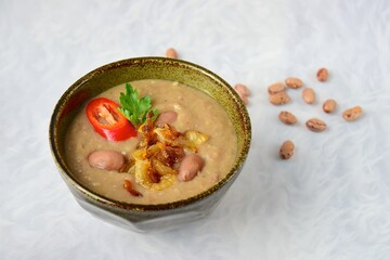 Borlotti bean or cranberry bean soup garnish with caramelized onion, chili and parsley