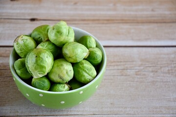 Fresh Brussel Sprouts in a bowl on wooden background