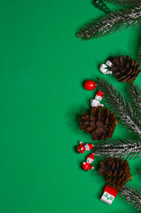 Christmas background, wooden christmas tree decorations, spruce or pine branch and cones on a green background, copy space for text or design, greeting card top view flatlay