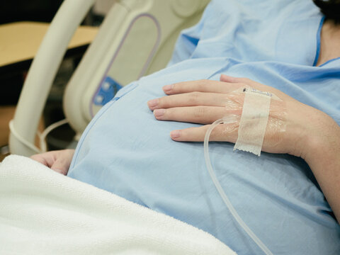 Pregnant Woman patient is waiting to deliver baby with drip receiving a saline solution on bed  at hospital, selective focus. Health Care concept, insurance concept, mother concept