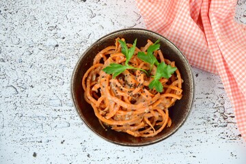 Fresh raw organic spiralized carrot noodle with tahini, parsley and sesame seeds