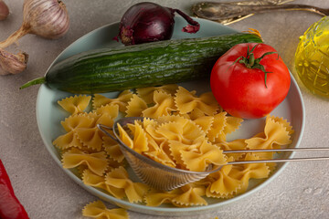 Vegetarian cooking pasta with vegetables, raw ingredients on light concrete background. close up