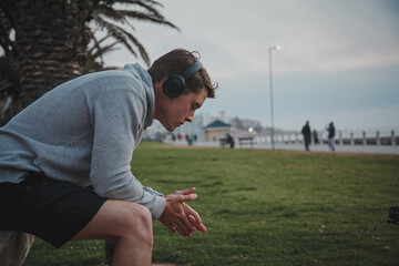 focused man sitting on bench listening to headphones
