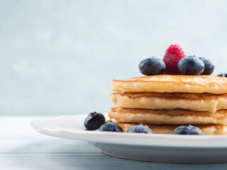 Stack of pancakes with fresh blueberries served in a dish with maple syrup. Delicious breakfast