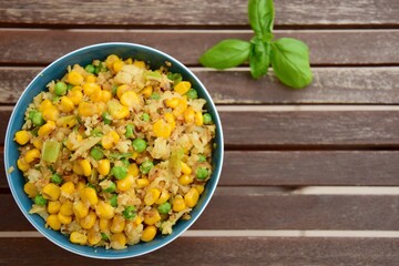 Cauliflower rice with corn and peas garnish with basil leaf