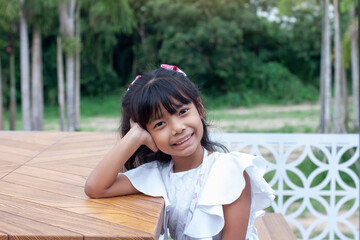 Asian little girl sitting happy mood arm on head while traveling on vacation.