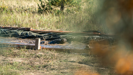 Athletes crawling in mud under barbed wire at an obstacle course race