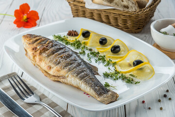 Fish with lemon and herbs on wooden white aged background