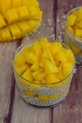 Mango coconut chia seeds pudding in glasses on wooden background