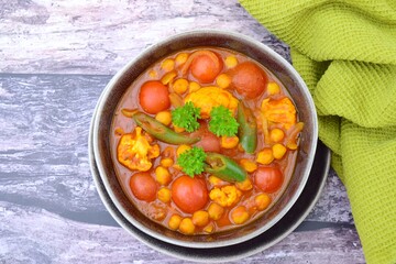 Spicy chickpea cauliflower tomato soup with green chili and parsley. Top view
