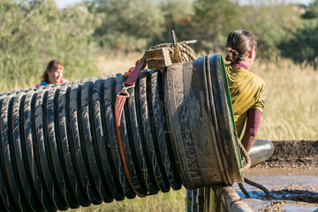 Female athlete climbing out of a pipe at an obstacle course race