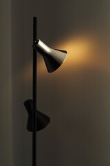 Fototapeta Czarna stylowa stojąca lampa na tle białej ściany. Gra światła i kolorów. obraz