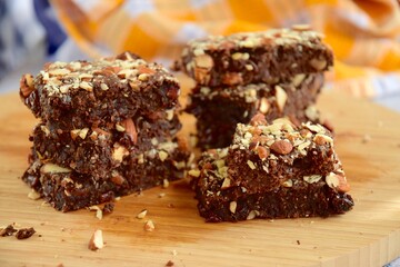 Fudge brownies dark chocolate cake topping with almond nuts on wooden board