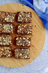 Fudge brownies dark chocolate cake topping with almond nuts on wooden board