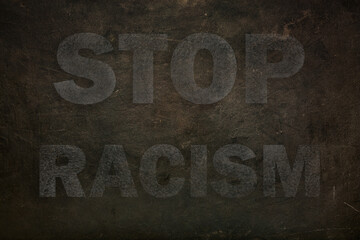 Font with transparency STOP RACISM graffiti on a black stone background. close up
