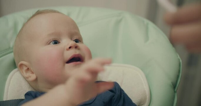 Mother's hand tries playfully to measure temperature in the mouth of her baby