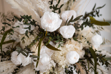 Pastel colored autumn bouquet of white flowers and dry fluffy grass. Floral background