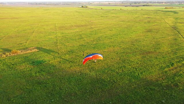 Motor paraglider starts to take off on the field, but the pilot makes a mistake when taking off and lifting the wing and the wing descends to the grass. Aerial view.
