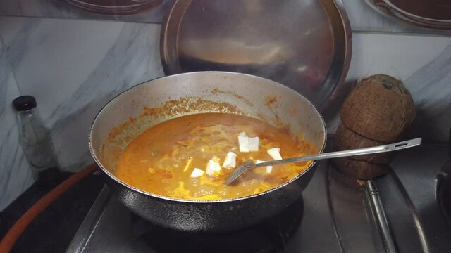 Putting homemade paneer blocks in spicy gravy for dinner
