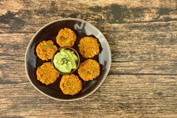 Homemade chickpea patties with guacamole dip and black sesame seeds. Flat lay

