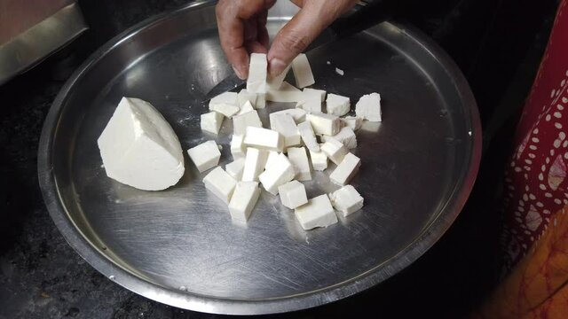 A hand is seperating homemade paneer for dinner preparations