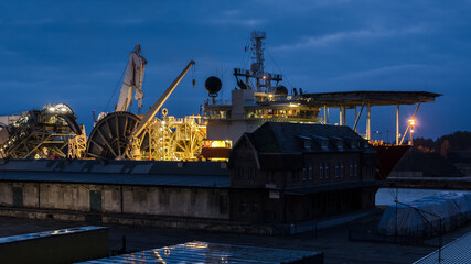 SHIP IN SEAPORT - Specialized watercraft moored at the wharf against the background of warehouse infrastructure