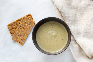 Mushroom cream soup in ceramic bowl with crispbread. Home cooked meal. Top view.