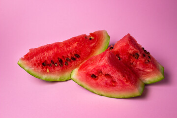 Watermelon on a pink background. Cut off a slice of watermelon. Red ripe watermelon