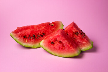 Watermelon on a pink background. Cut off a slice of watermelon. Red ripe watermelon