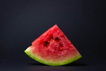 Fototapeta na wymiar Watermelon on a black background. Cut off a slice of watermelon. Red ripe watermelon