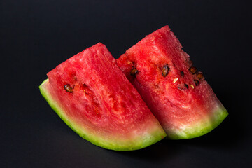 Watermelon on a black background. Cut off a slice of watermelon. Red ripe watermelon