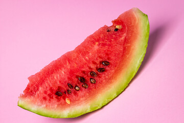 Watermelon on a pink background. Cut off a slice of watermelon. Red ripe watermelon