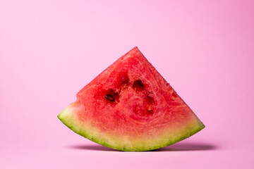 Watermelon on a pink background. Cut off a slice of watermelon. Red ripe watermelon