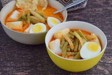 Lontong Sayur, Indonesian cuisine. Compressed rice cake or lontong with vegetables (chayote and yard long beans) cooked in coconut milk and spices. Served with boiled egg and emping cracker