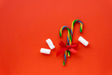 Christmas lollipop canes with bow and marshmallow on a red background, space for text