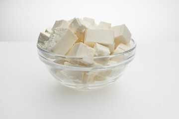 Feta cheese closeup cut into cubes in a transparent bowl, top view