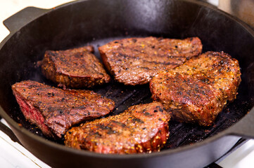 Cooked, fried, juicy marbled beef on a grill pan, with spices.