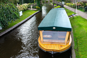 A wooden excursion boat moored in the channel is connected by a cable to the socket in order to...
