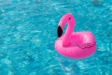 Summer time. Pink inflatable flamingo in pool water for summer beach background. Funny bird toy for kids.