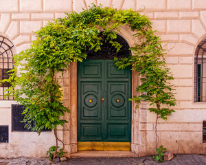Fototapeta na wymiar vintage house entrance green door and foliage, Trastevere picturesque neighborhood, Rome Italy