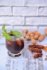 Iced tamarind juice with mint leaf, ripe tamarind fruit and seeds 