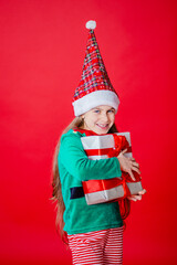 Merry Christmas, happy attractive girl with gifts in a costume of Santa Claus helper elf on a bright red bright color background.