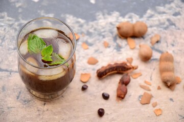 Iced tamarind juice with mint leaf, ripe tamarind fruit and seeds 