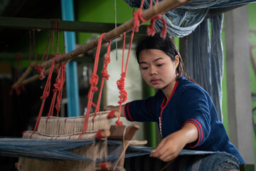Traditional Isan Thai Cotton indigo weaving. Young women weaving indigo-dyed cotton.