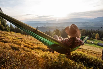 Photo sur Plexiglas Camping Randonneur de femme se reposant après avoir grimpé dans un hamac au coucher du soleil