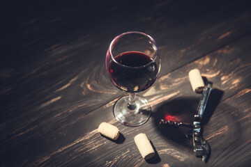 glass of wine and corks with opener