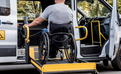 A man in a wheelchair on a lift of a vehicle for people with disabilities