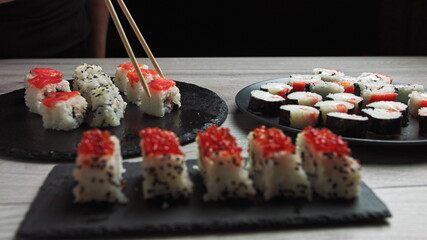 Set of Sushi Rolls with tuna, salmon, cucumber, avocado sprinkle with sesame seeds on black Background close-up. Assortment of Japanese food in restaurant.